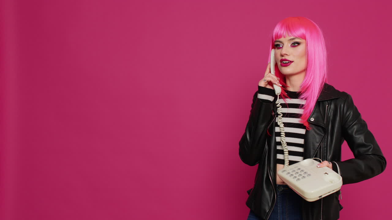 Attractive woman with pink wig talking on landline phone call