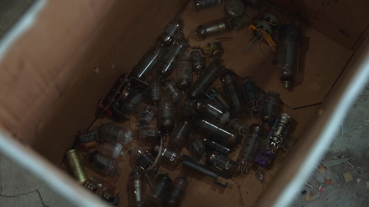 Box Filled With Vintage Vacuum Tubes, Dusty Cardboard Crate On Cracked Concrete Floor, Pile Of Glass Radio