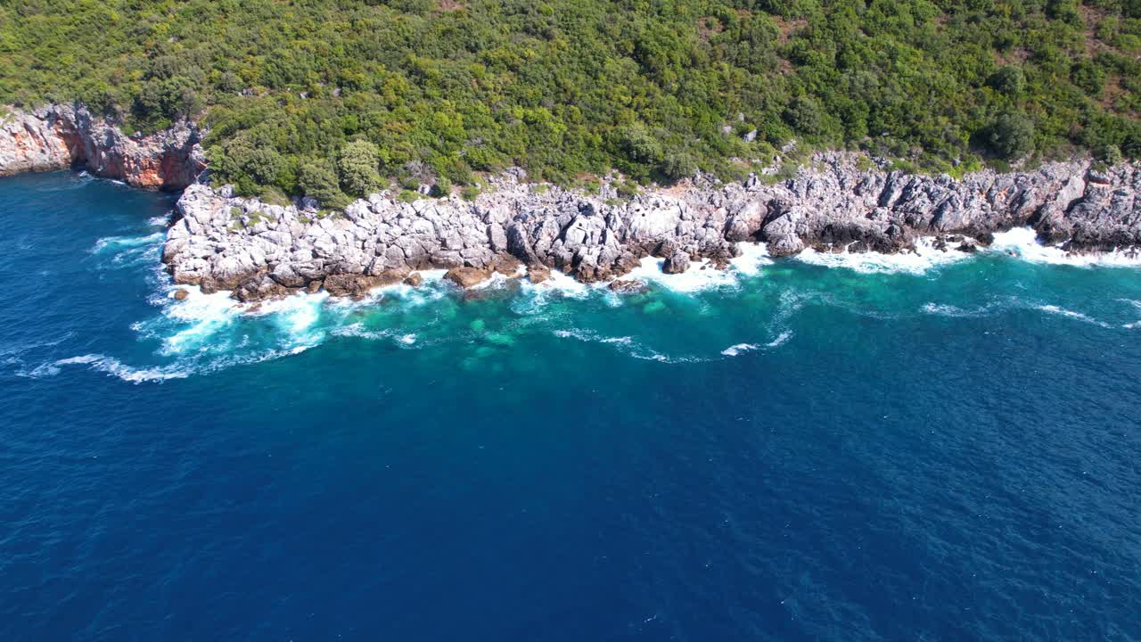 Costa selvaggia con pendii rocciosi bagnati dalle onde del mare nel Mediterraneo.