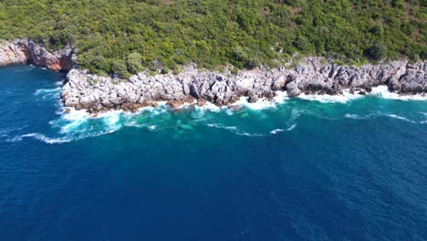 wild coastline with rocky slopes splashed by sea waves in mediterranean