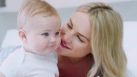 mother lying on bed at home gives baby son kiss