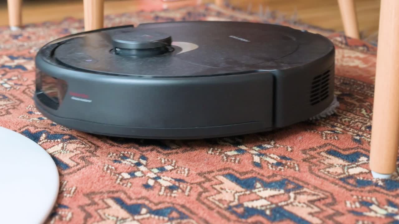 автономный робот-пылесос очищает и мопит ковер в гостиной, избегая ног стула благодаря избежанию препятствий