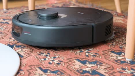 an autonomous robot vacuum cleaner cleans and mops a living room carpet while avoiding chair legs thanks to its obstacle avoidance