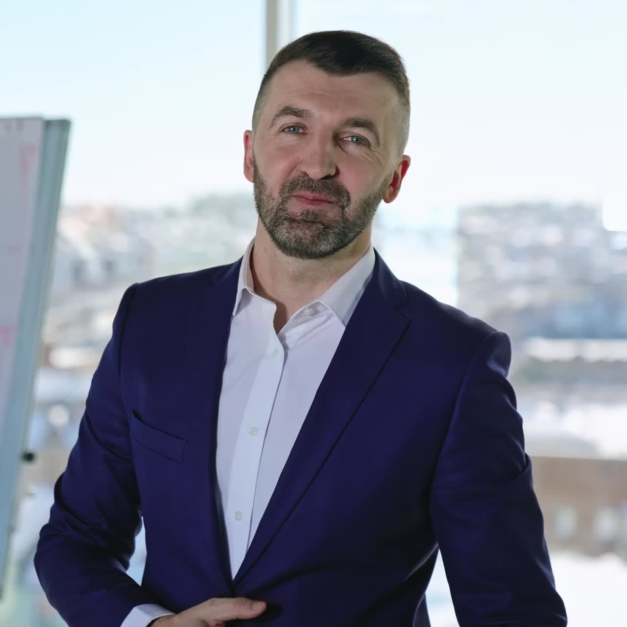 Smiling bearded professional businessman looking at camera. Confident handsome adult entrepreneur speaking in office. Face view business portrait close up