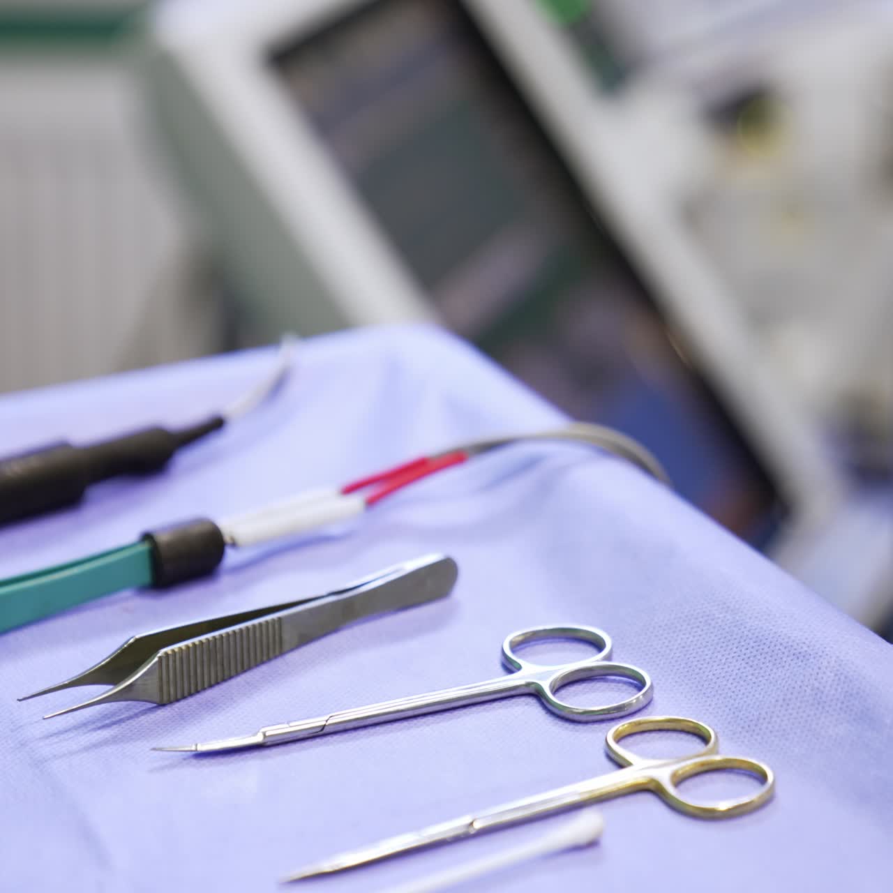 Surgical scissors, forceps and electric medical devices on the table in surgery room. Close up. Blurred backdrop