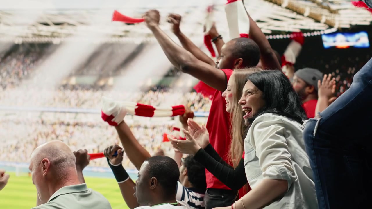 Aficionadas al fútbol celebrando un gol con los brazos en alto en las gradas abarrotadas del estadio.