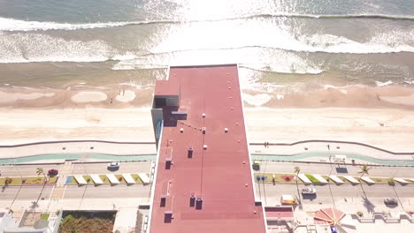 Jib-down-of-high-rise-rooftop-near-beautiful-beach-in-summer