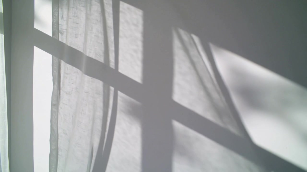 Swaying sheer curtain and shifting window-grid shadows in bedroom as breeze and sunlight drifting