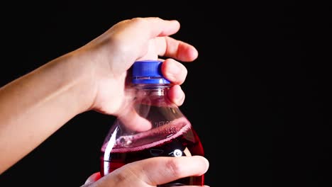 hands opening a red fizzy drink bottle