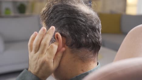 man with earache is in pain and massaging his ears with his hands.