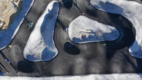 children, unrecognizable, ride bicycles on pump track still under construction, urban recreation and outdoor fun, offroad bike skills and recreation, aerial zoom out