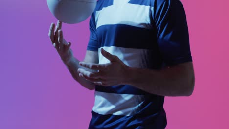 caucasian male rugby player with rugby ball over pink lighting