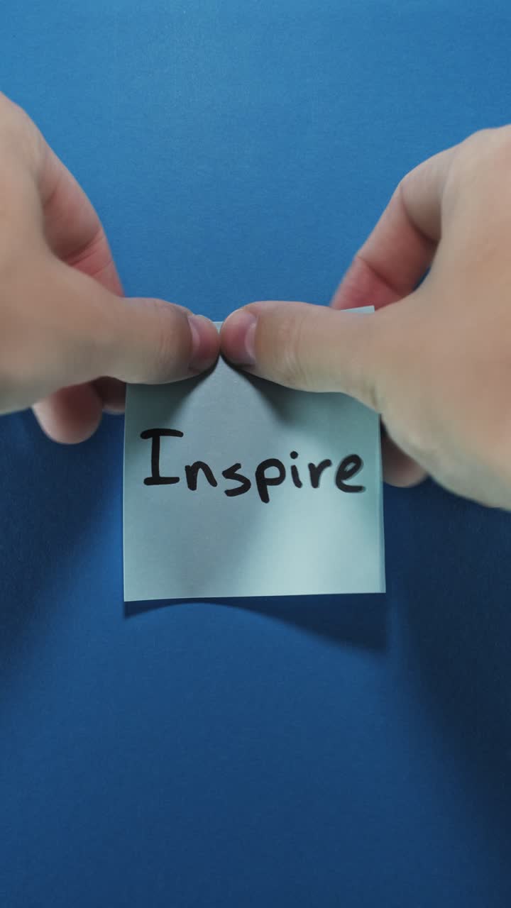 Portrait shot of a light blue sticky note reading "Inspire" on a deep blue background