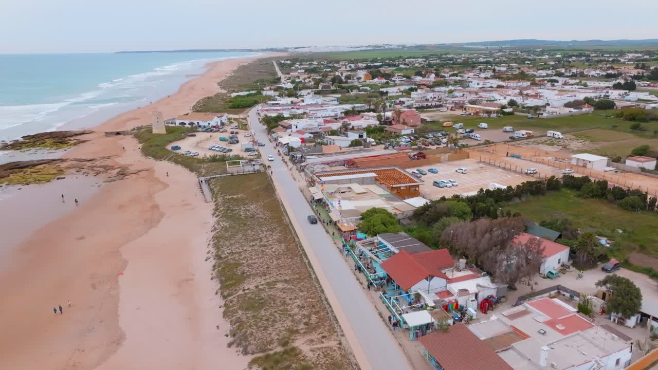 pacífico camino junto al océano con casas pintorescas y amantes de la playa que surfean al atardecer
