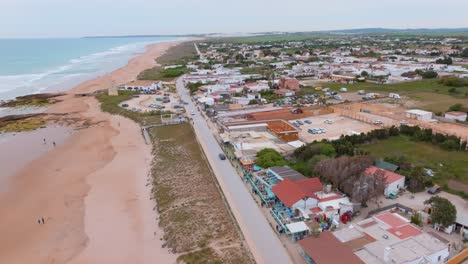 Peaceful-Oceanside-road-with-quaint-homes-and-beach-goers-surfing-at-sunset