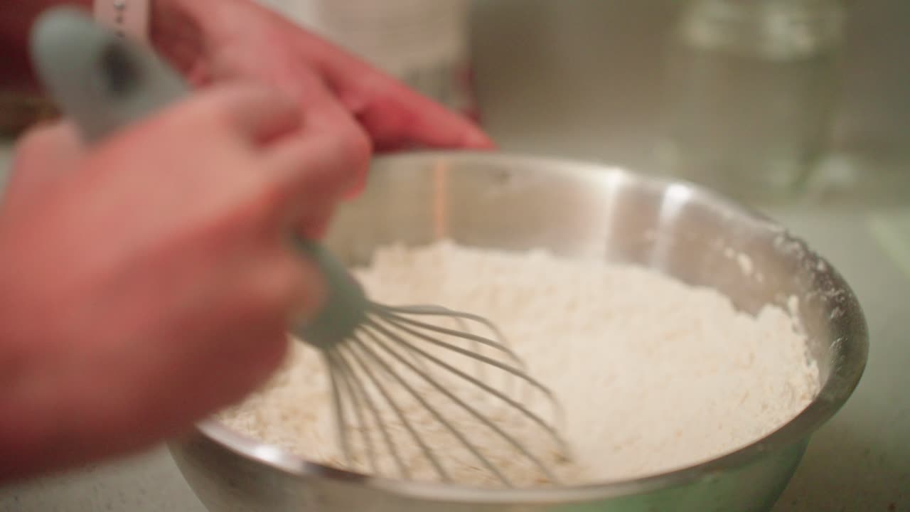 Woman mixing dry dough ingredients with a whisk