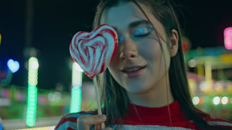 closeup funfair girl posing holding lollipop. smiling female walking luna park