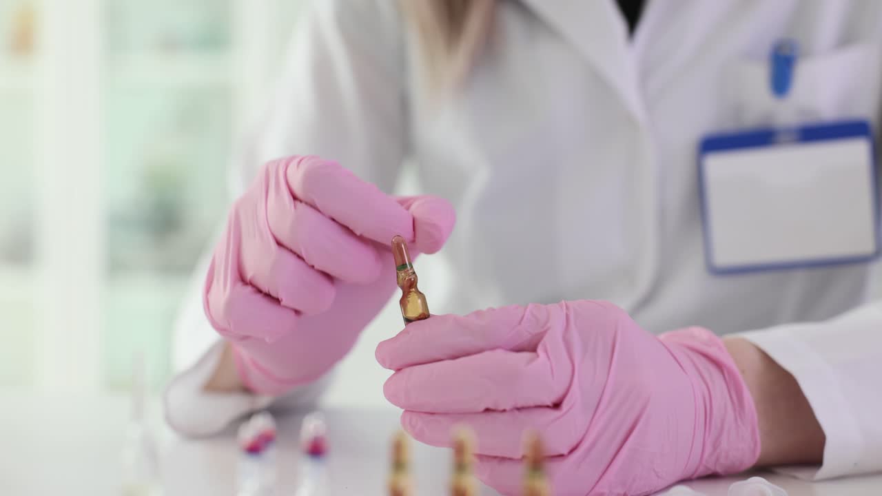 Scientist in pink gloves holding an ampoule in a lab