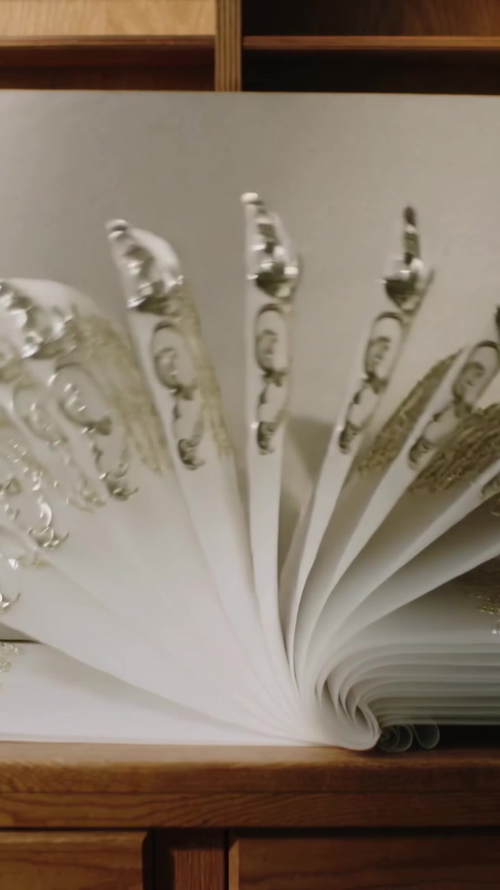 Video verticale: Libro che viene sfogliato mentre il dorso si apre, si apre a ventaglio, si richiude, mostrando i bordi dorati su uno scaffale.