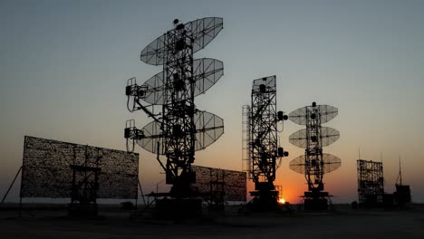 silhouetted radar towers against a sunset sky: a stunning display of technology in harmony with nature's evening palette
