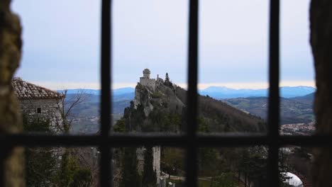 panoramic-view-from-a-window-with-bars-of-ancient-medieval-San-Marino-fortress-on-a-winter-cloudy-day