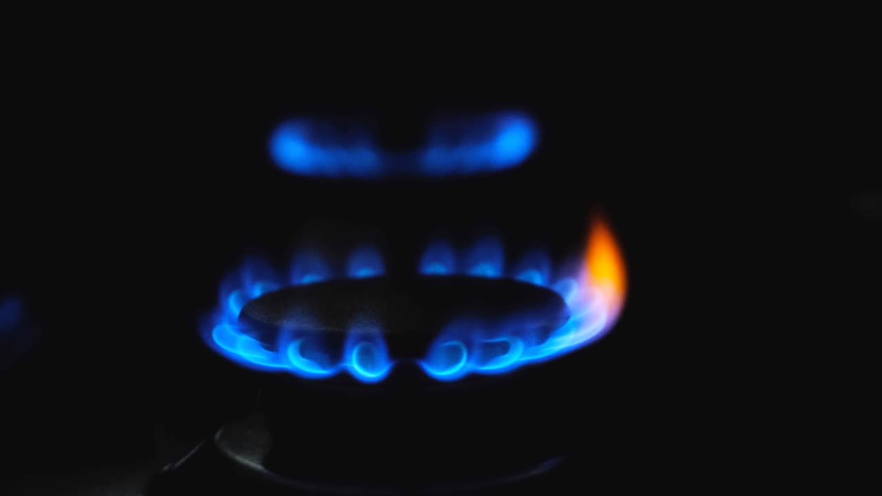 검은색 배경에 있는 가스 스토브의 파란 불꽃. 가스가 켜지고 있다.