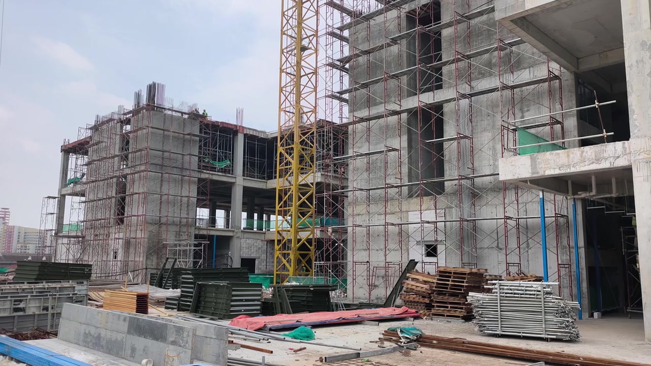 Construcción activa de un edificio de gran altura en curso. Se aplican estrictas medidas de seguridad en el lugar. Los materiales pesados están organizados de forma ordenada para un flujo de trabajo eficiente.