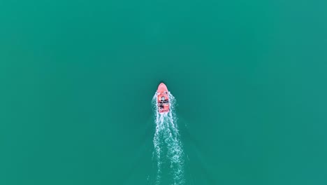 Birdseye-view-tracking-motorboat-gliding-through-green-water