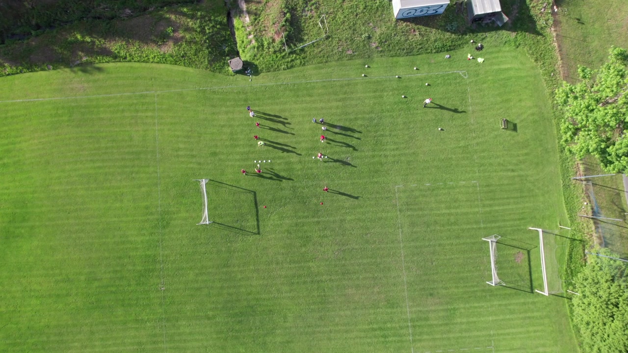 Entrenamiento de fútbol, vista aérea cenital con sombras, equipo realizando ejercicios con balón, 4K.