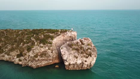 Junger-Mann,-Der-Am-Ende-Einer-Felsigen-Klippe-Am-Ozean-In-Providenciales-Im-Turks--Und-Caicos-Archipel-Steht