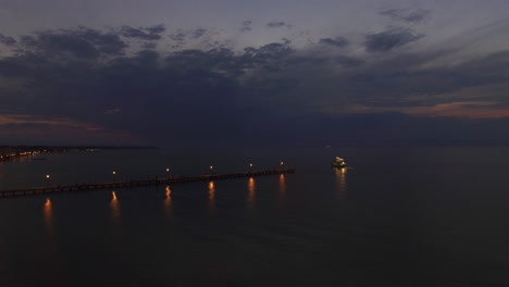 Flying-over-sea-pier-and-sailing-boat-at-night