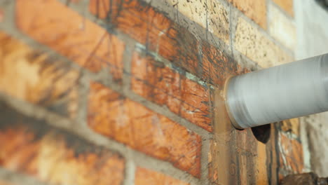 un taladro con punta de diamante perfora un agujero en una pared de ladrillos