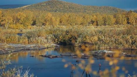 a professional camera mounted on a slider rig is positioned on the riverbank filming the autumn tundra landscape