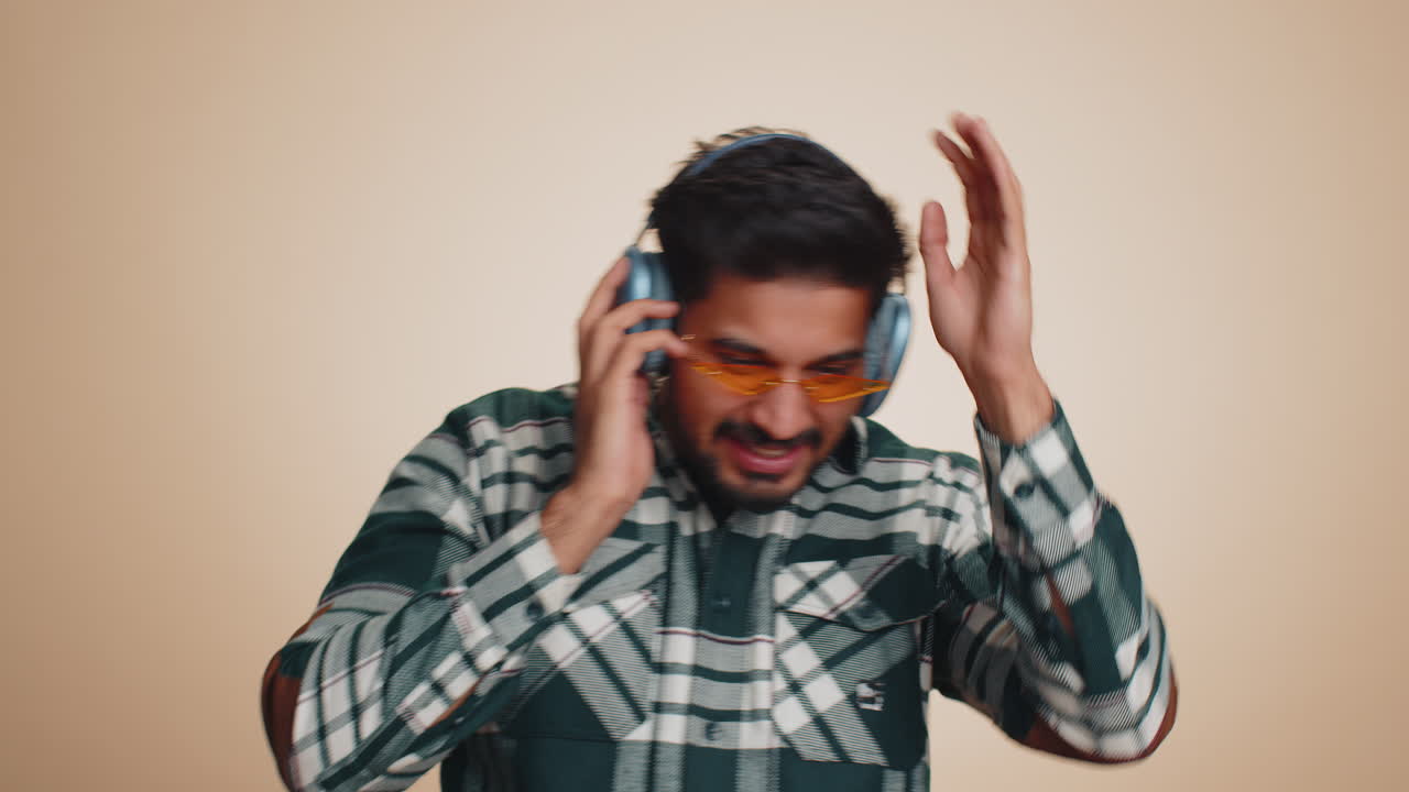 Un uomo indiano felice con le cuffie che ascolta musica, danza, discoteca, si diverte, si rilassa alla festa di Natale.