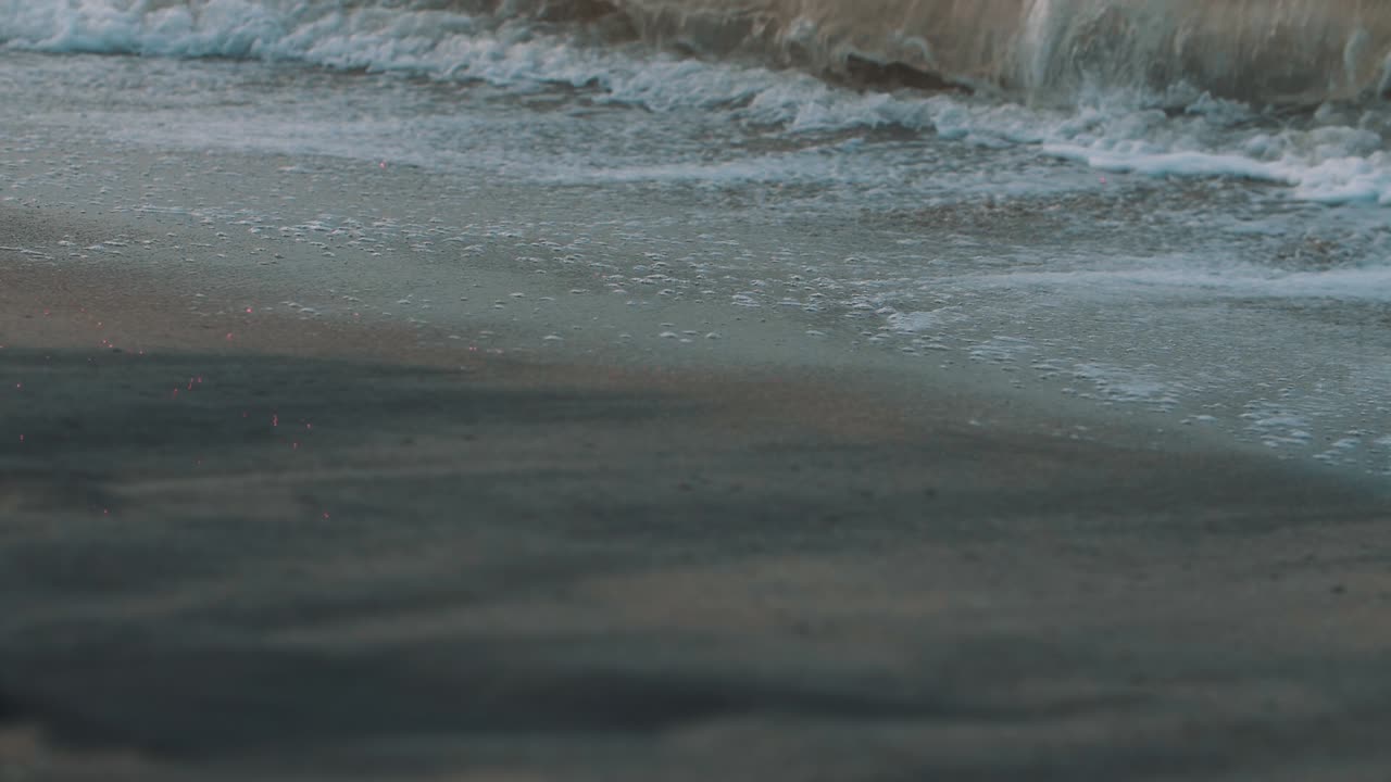 Foam of the waves crashing on the sand of the beach - Beautiful close-up, macro, slow-motion shot