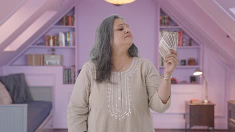 confident indian old woman using money as fan