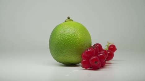 Frisch-Gepflückte-Rote-Johannisbeeren-Und-Grüne-Limette,-Die-Sich-Im-Uhrzeigersinn-Drehen-–-Nahaufnahme