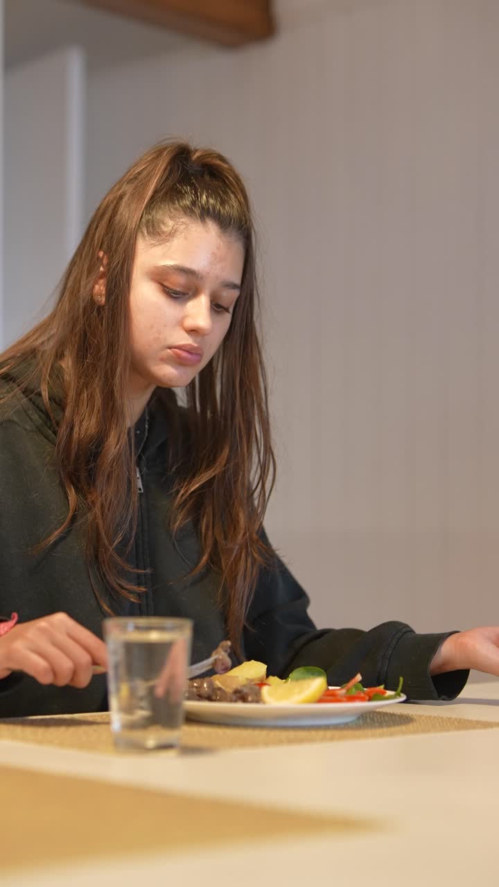 una adolescente comiendo la cena.