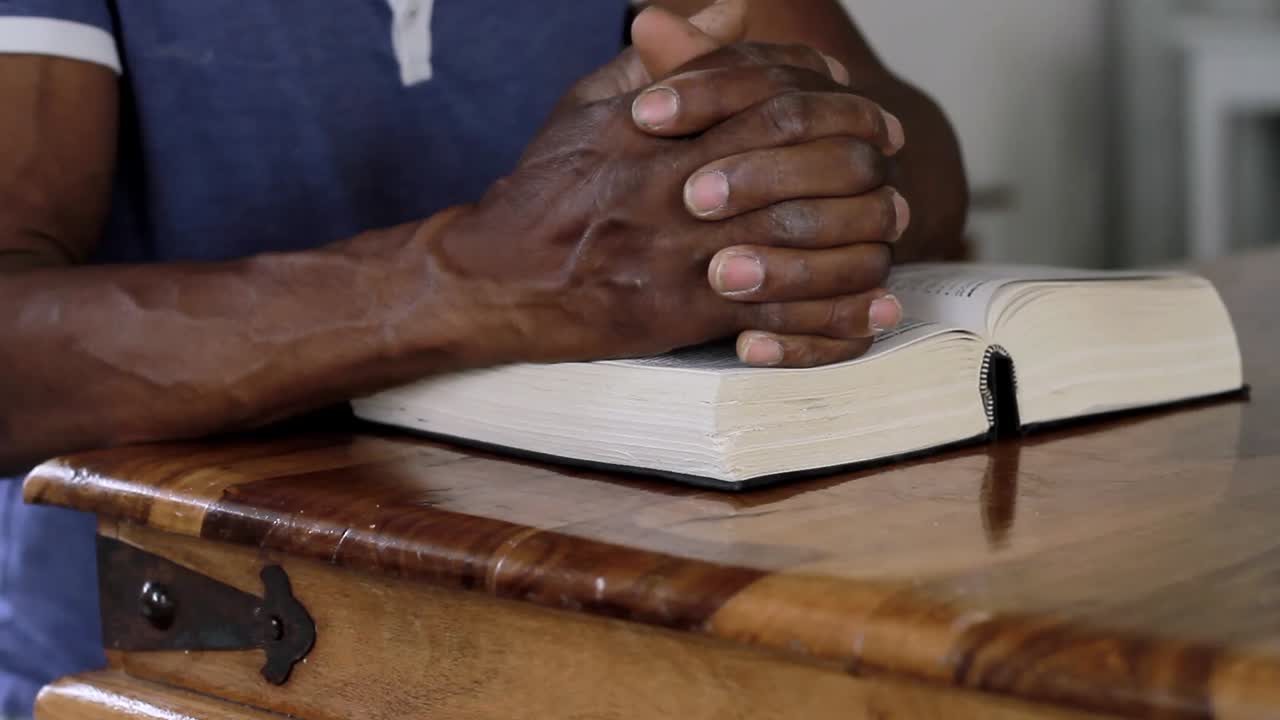 Muž modlící se k Bohu s rukou na bibli, s lidmi, stock video záběry.