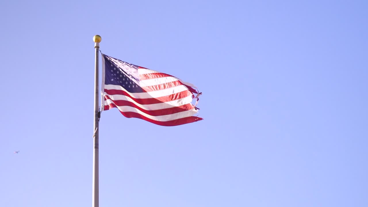bandera de los estados unidos ondeando, en el fondo un cielo azul