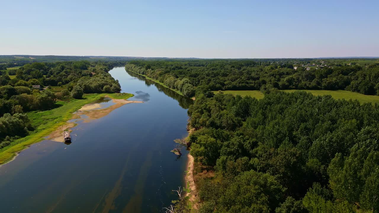 La Vienne river winding through lush green countryside near Chinon under blue summer sky, aerial tracking left establish