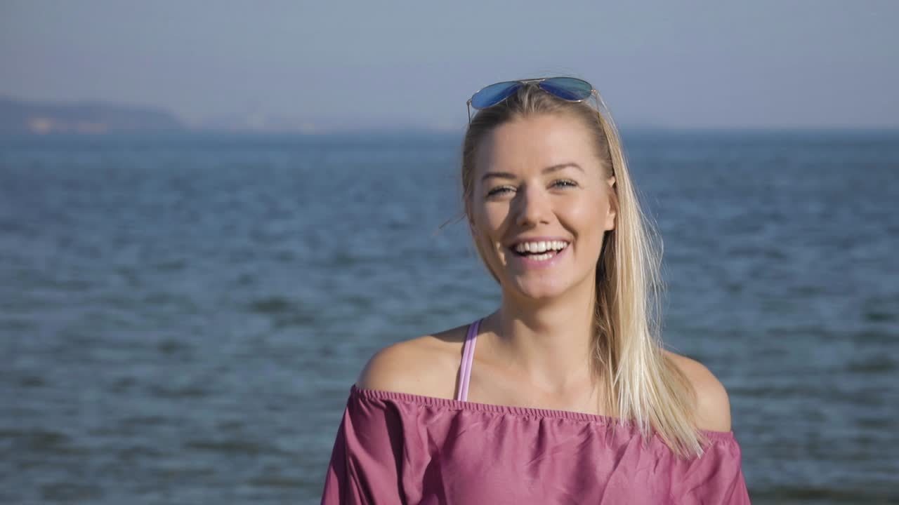 sonrisa cálida y genuina en una bonita mujer rubia en la playa.