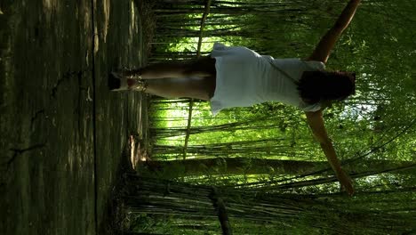 slow motion dolly shot of a young woman in white dress walking through an avenue of plants in bali indonesia