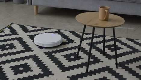 white robot vacuum cleaner sucking dust on a carpet in a modern living room