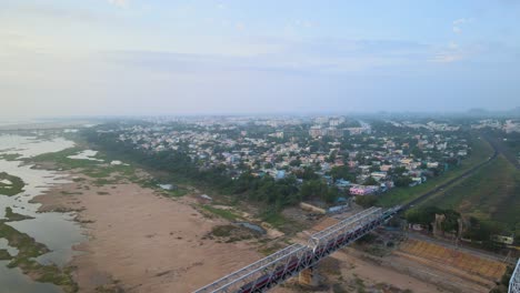 aerial drone shot capturing an indian train as it moves swiftly through the heart of the city, showcasing the urban rhythm.