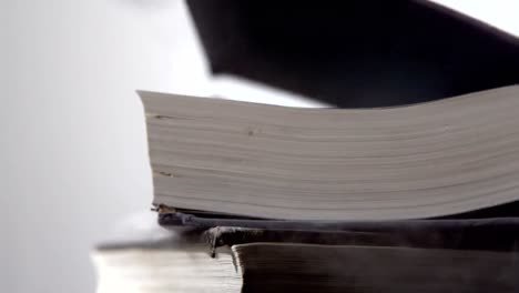 Heavy-black-books-falling-on-white-surface