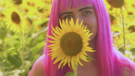 Turning-toward-the-camera-a-beautiful-pink-haired-woman-holds-a-yellow-sunflower