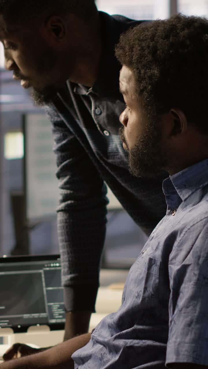 Vertical video IT specialist assisted by coworker to compare data in office