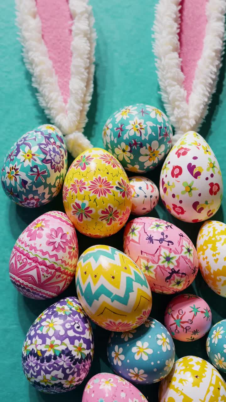 Top-down video style shot of colorful, intricately patterned Easter eggs arranged with bunny ears