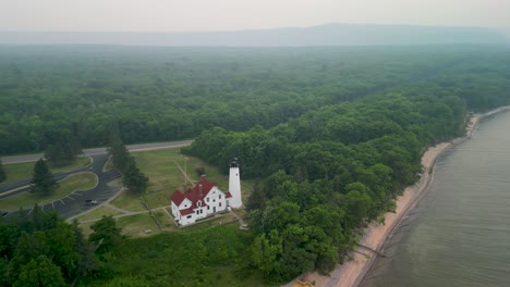 Aerial-orbit-of-Point-Iriquois-Lighthouse-in-Canadian-wildfire-smoke,-Lake-Superior,-Michigan